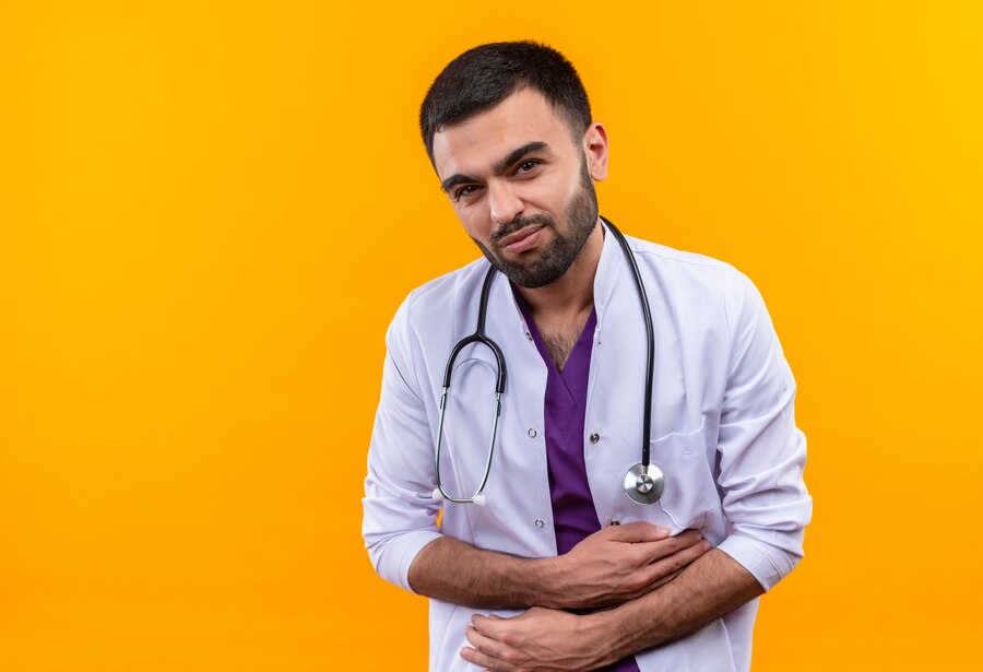 sick-young-male-doctor-wearing-stethoscope-medical-gown-grabbed-aching-stomach-isolated-yellow-background