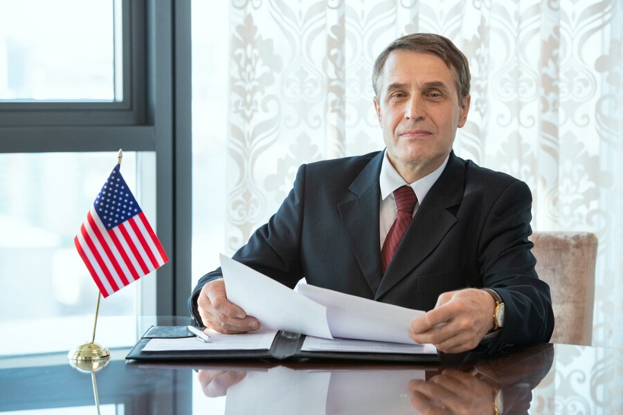 successful-american-delegate-businessman-elegant-suit-looking-through-contract-business-partnership-while-sitting-by-workplace
